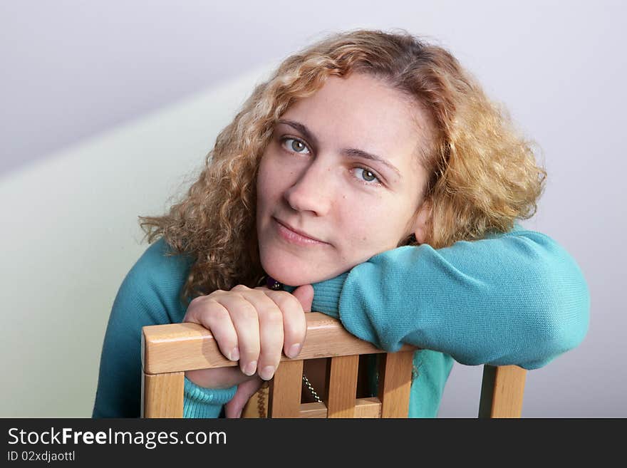 Portrait of a woman with a blond curly hair sitting on a chair. Portrait of a woman with a blond curly hair sitting on a chair