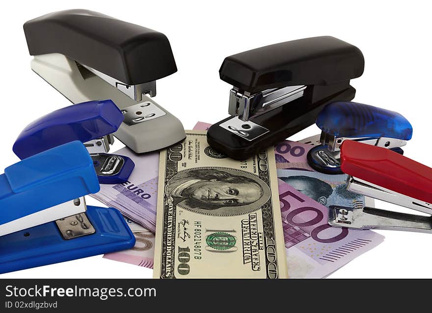 Banknotes of various currencies in an environment of staplers of the different sizes and colors. Symbolizes interrelation of various world currencies. Banknotes of various currencies in an environment of staplers of the different sizes and colors. Symbolizes interrelation of various world currencies