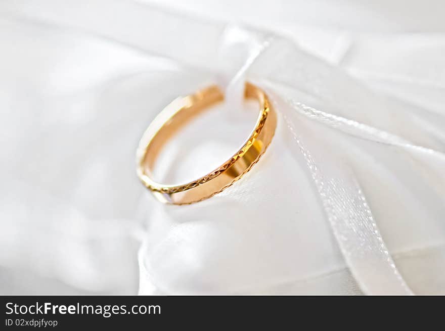 Classic gold wedding ring on white satiny fabric. Classic gold wedding ring on white satiny fabric