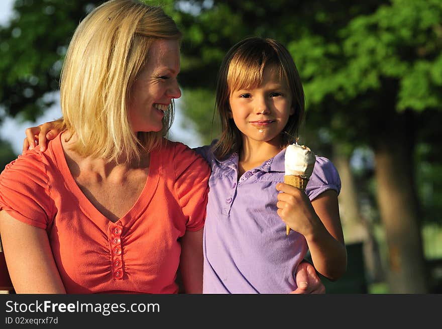 Loving mother watching her little girl eating ice cream. Loving mother watching her little girl eating ice cream