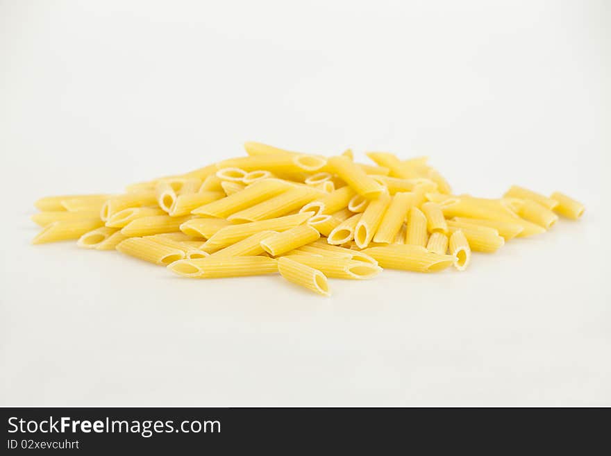 Scattered yellow pasta in the shape of a cylinder on the white backgrand