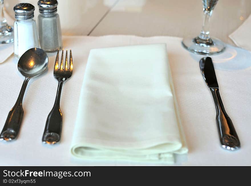 Restaurant table layout with white kitchen utensils before meals.