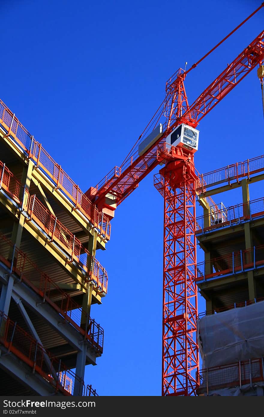 Image of a crane working on construction of a building under the blue sky. Image of a crane working on construction of a building under the blue sky