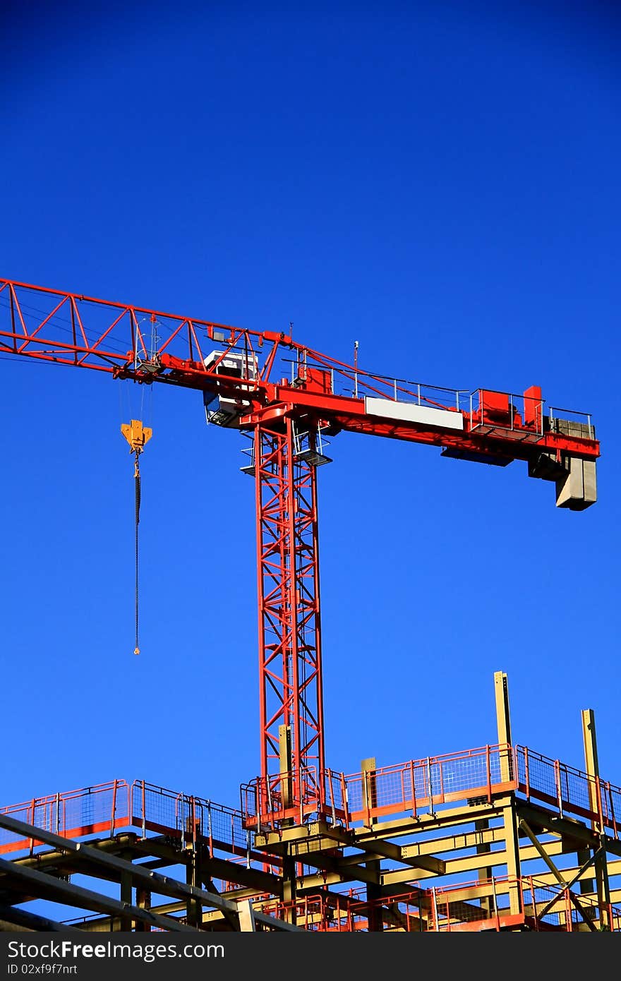 Image of a crane working on construction of a building under the blue sky