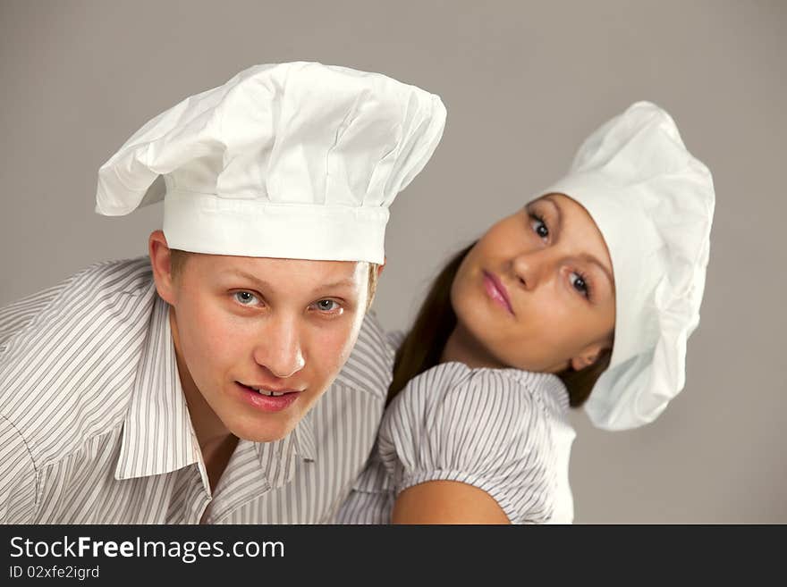 Young loving couple cooks. Over gray background