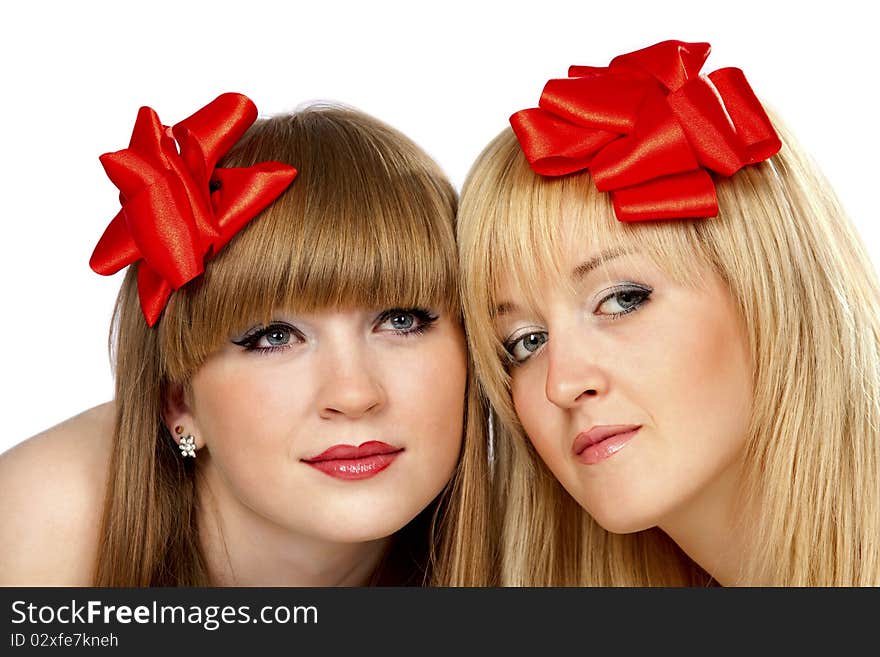 Portrait of two smiling young women with gift red bow over white background