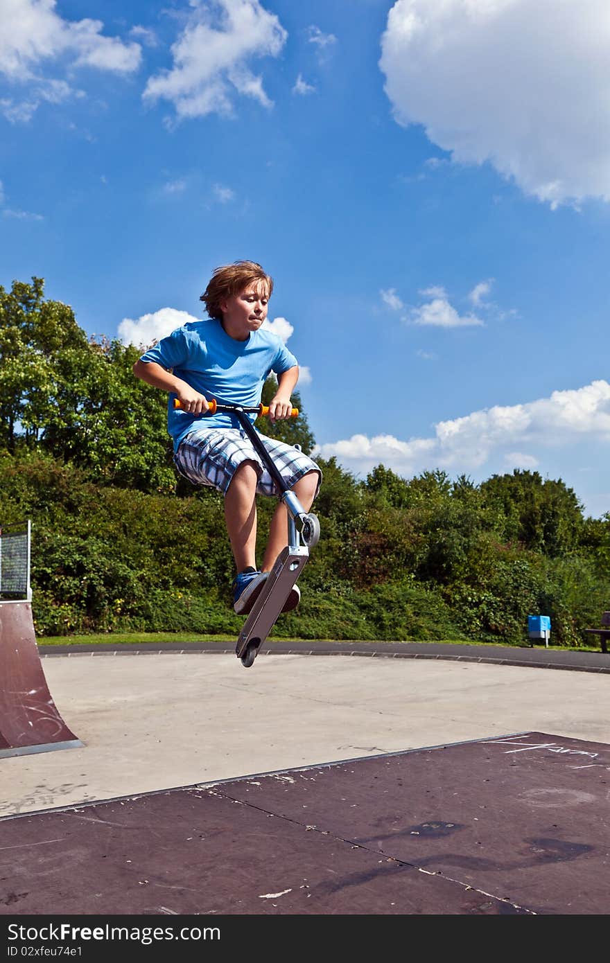 Young boy going airborne with his scooter at the skate park