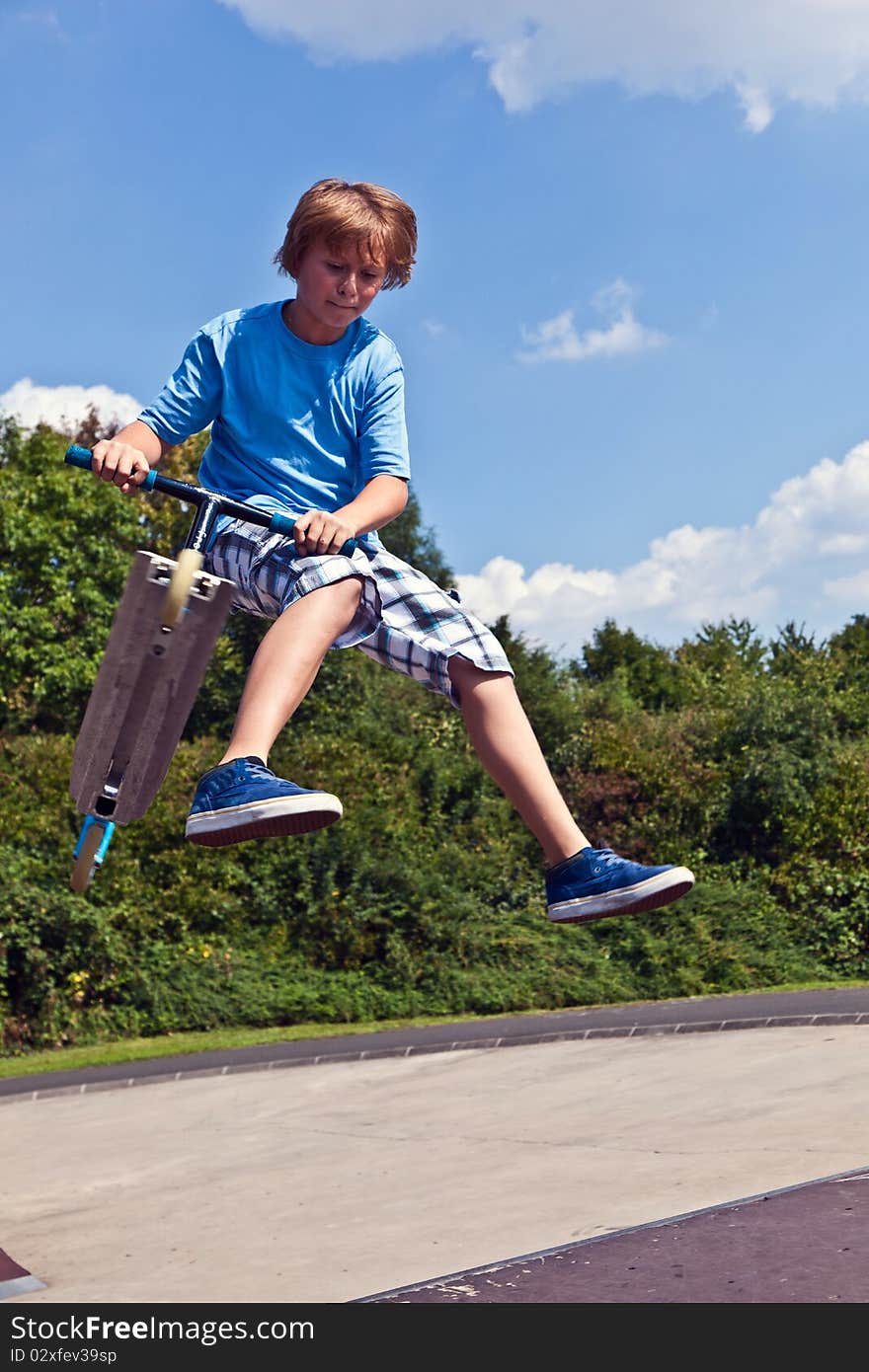 Young boy going airborne with his scooter at the skate park