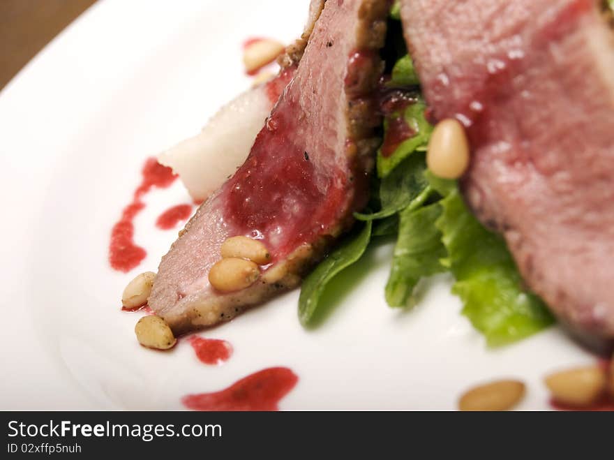 Meat with salad and nuts  served on the white  plate. Meat with salad and nuts  served on the white  plate