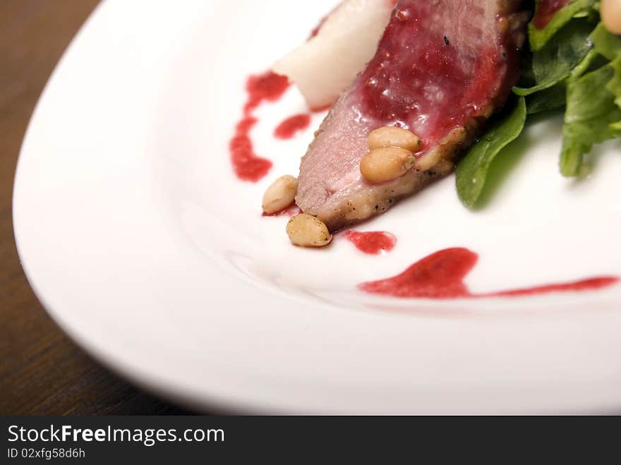 Meat with salad and nuts  served on the white round  plate. Meat with salad and nuts  served on the white round  plate