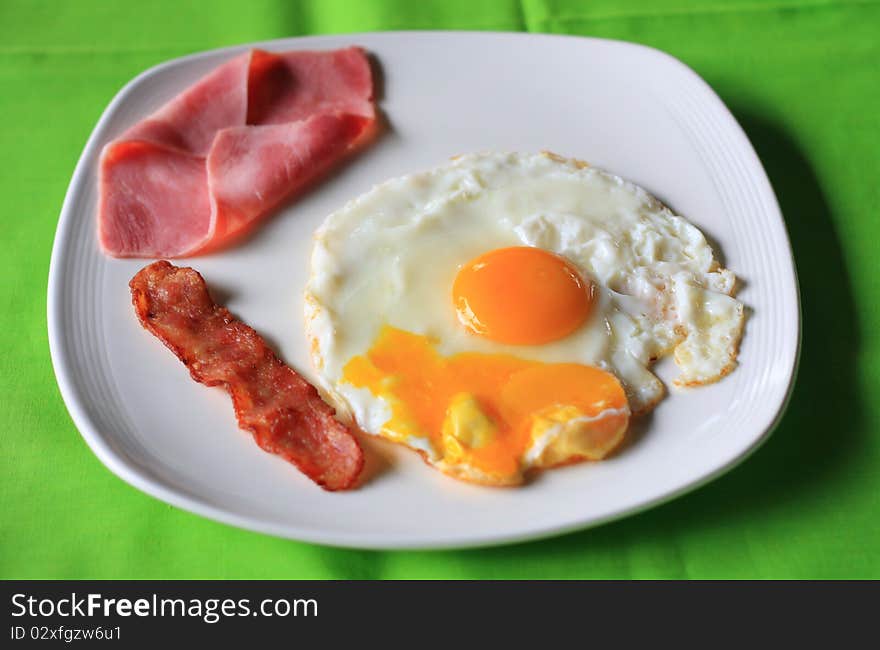 A high-calorie breakfast of fried egg, sausages, close-up in a non-stick pan.