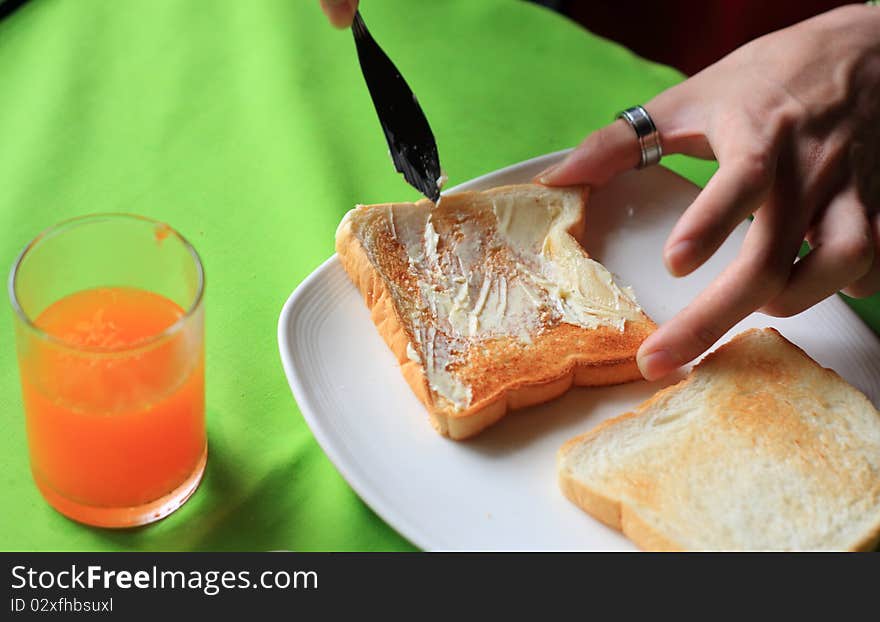 Knife spreading butter on toast in white plate. Knife spreading butter on toast in white plate