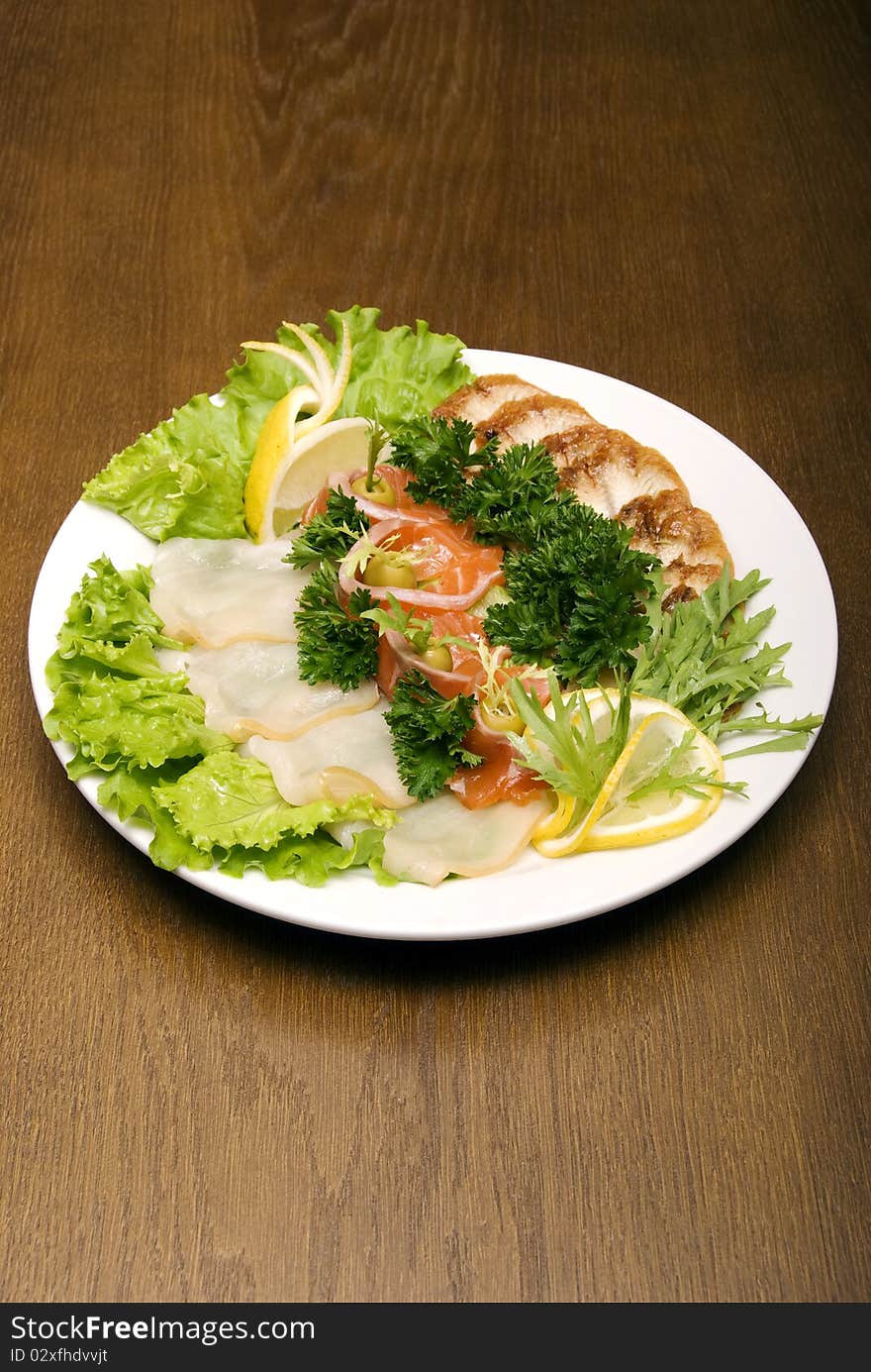 Appetizer made of meat and fish served with salad on the round plate