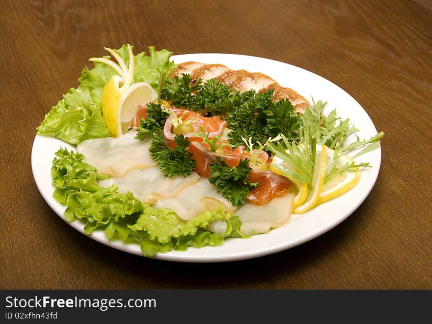 Appetizer made of meat and fish served with salad on the round plate