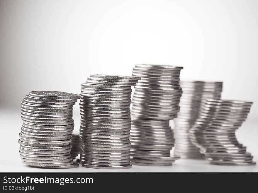 Stacks of coins, casting shadow on white.