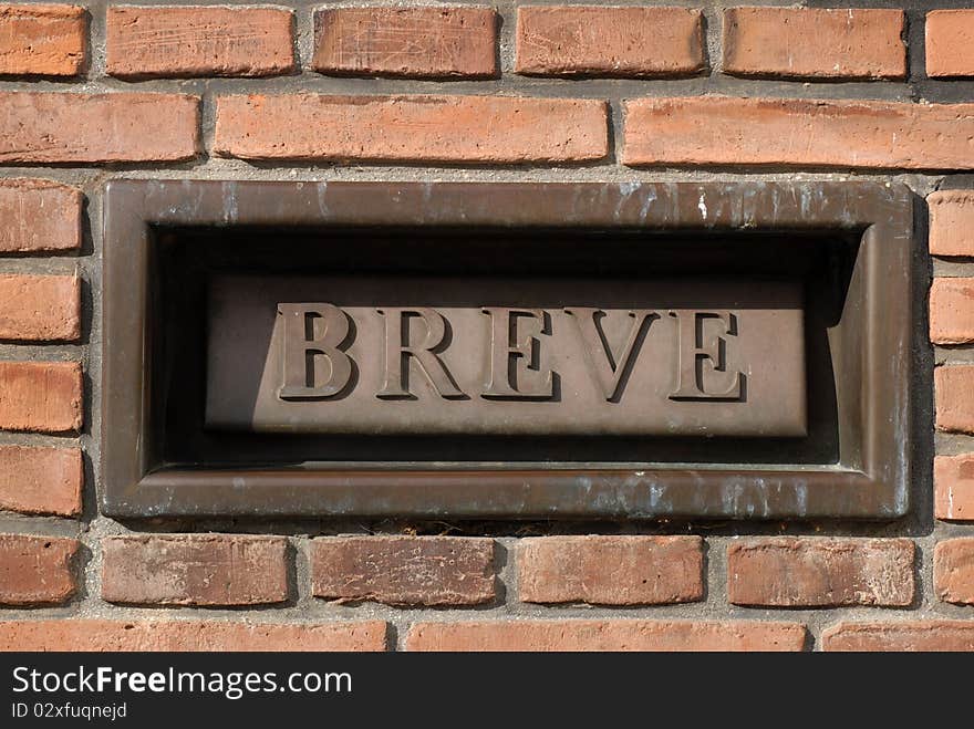 Danish letterbox in a solid brickwall with the word BREVE. In english LETTER.