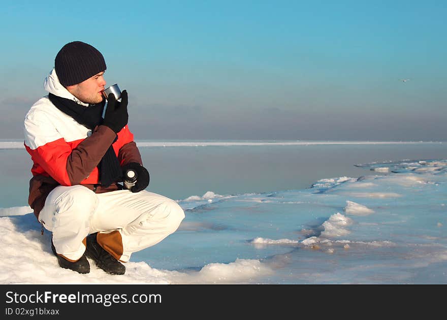 Young handsome man drinks hot tea/coffee in Nothern Pole