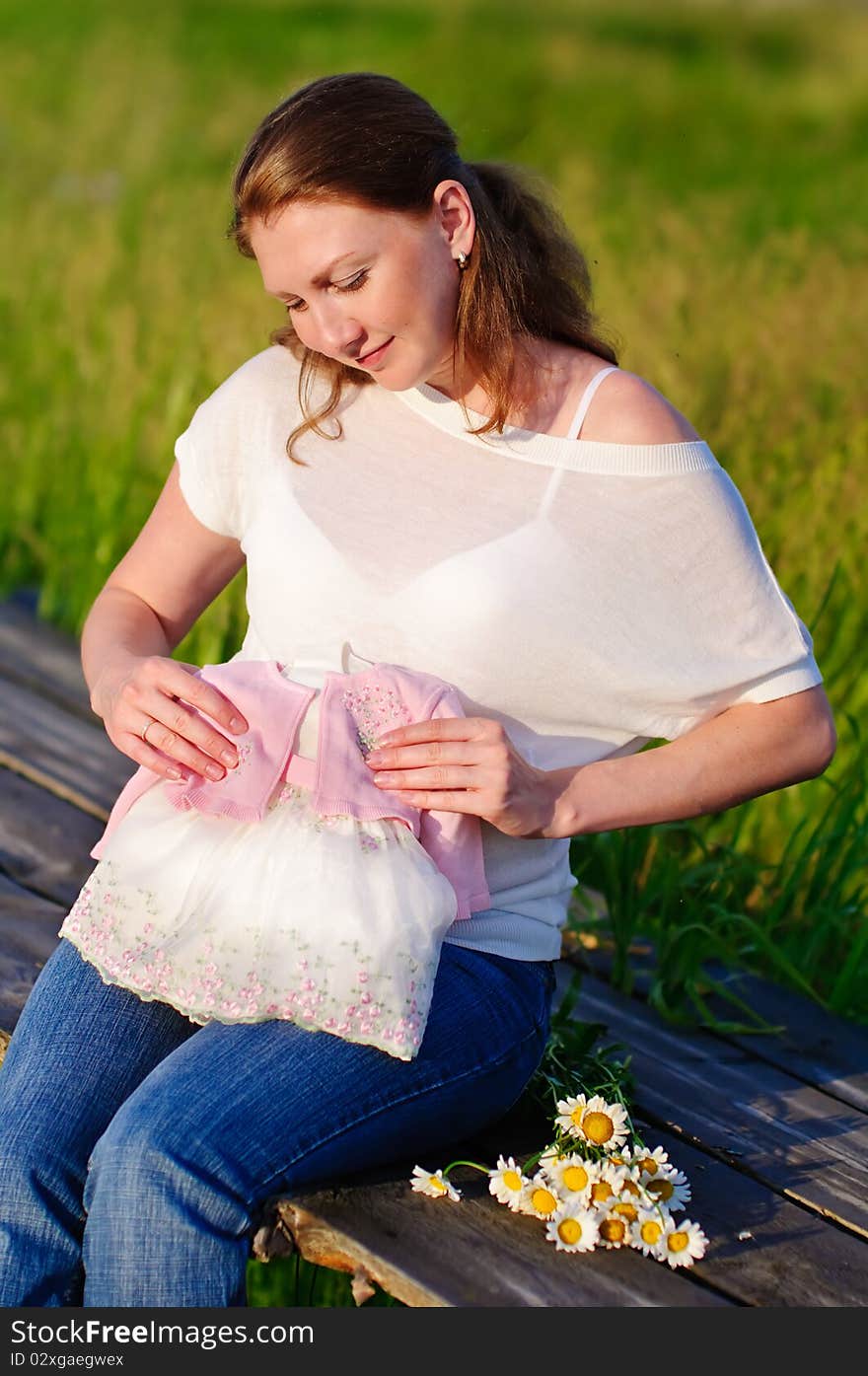 Pregnant woman with first cloth for her newborn baby outdoor. Pregnant woman with first cloth for her newborn baby outdoor