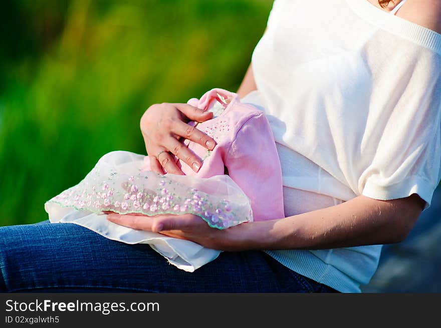 Pregnant woman with first cloth for her newborn baby outdoor. Pregnant woman with first cloth for her newborn baby outdoor