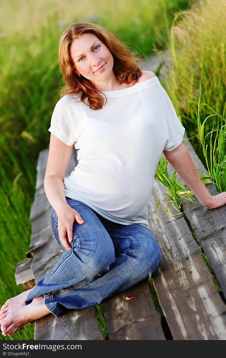 Portrait of beautiful happy pregnant woman on meadow