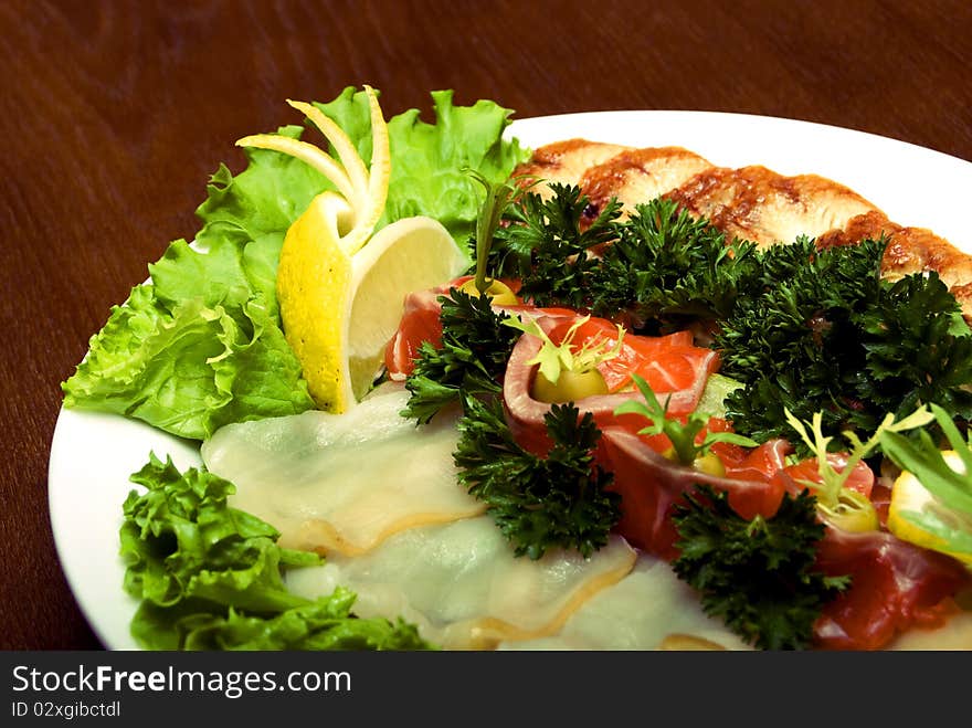 Appetizer made of meat and fish served with salad on the round plate