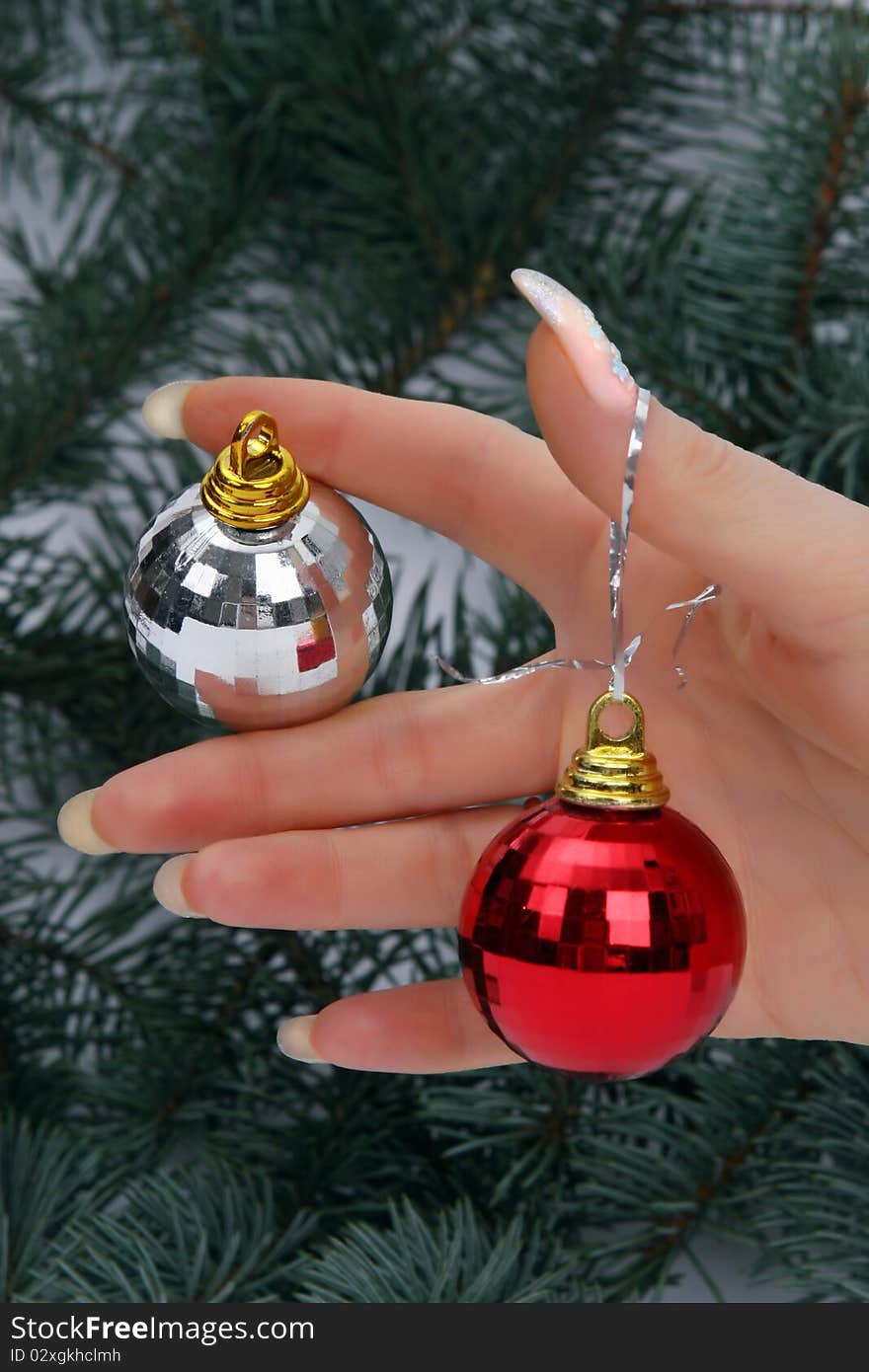 Female hand holding a Christmas ball on fur-tree natural background. Female hand holding a Christmas ball on fur-tree natural background