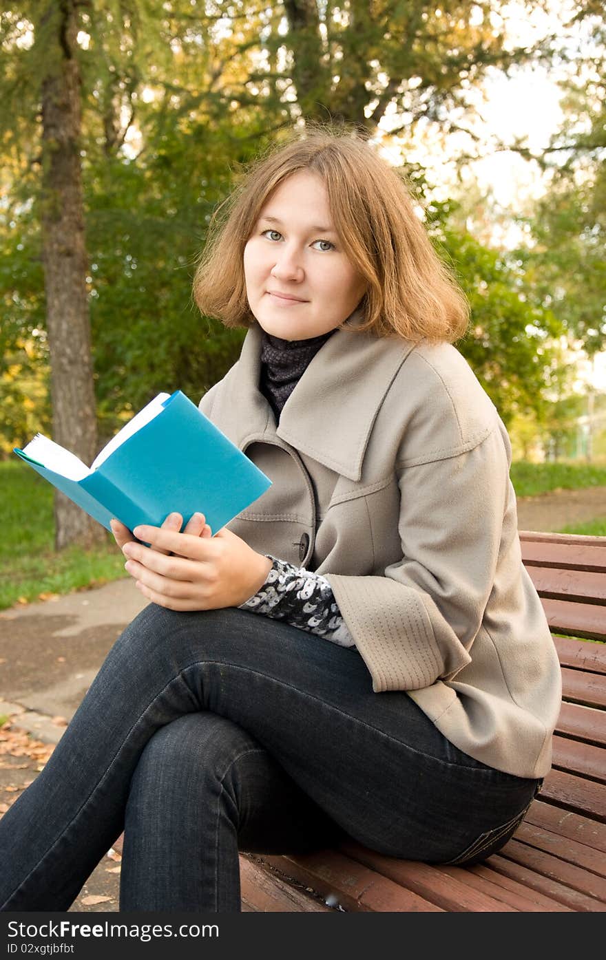 Adorable woman is sitting on the bench and reading a book. Adorable woman is sitting on the bench and reading a book