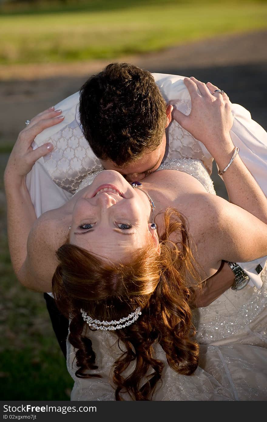 Just married couple with groom kissing bride in the cleavage on a sunny day