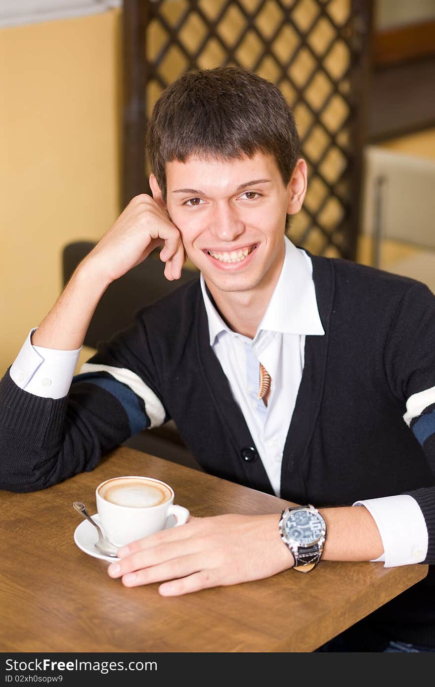 Young man with cup of coffee in cafe