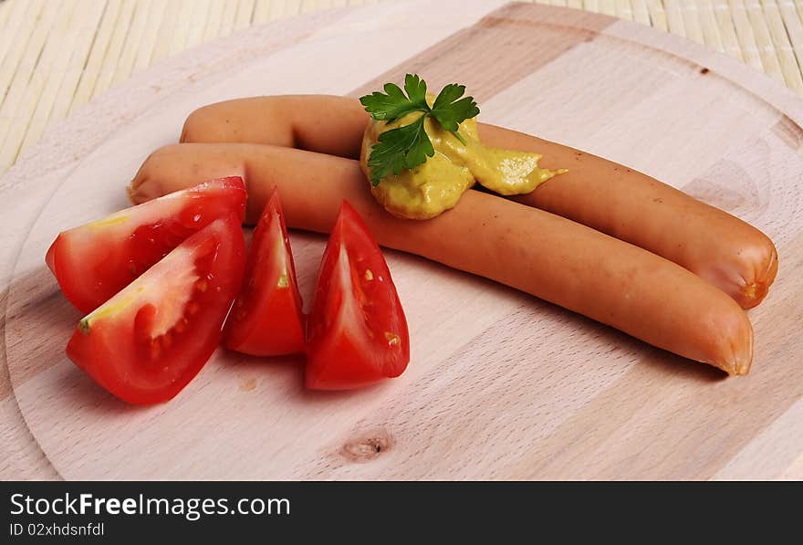 Tasty sausages on  platter with tomatoes and mustard. Tasty sausages on  platter with tomatoes and mustard