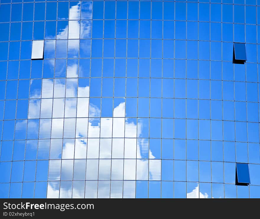 Highrise glass building with sky and clouds reflection.