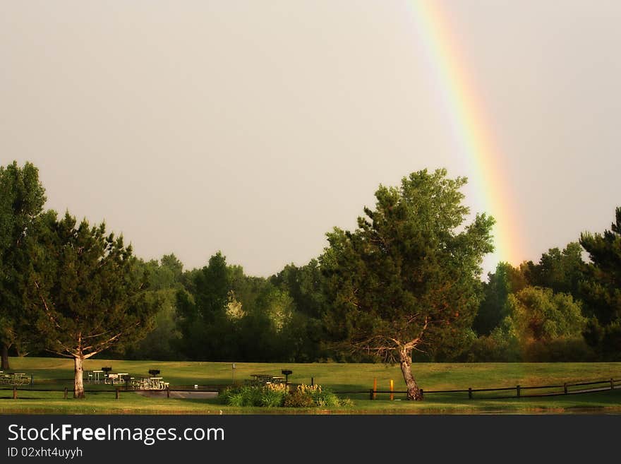 Rainbow in a blue sky over trees in a park. Rainbow in a blue sky over trees in a park