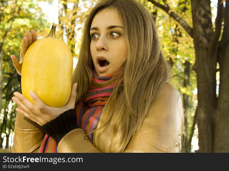 The frightened young woman holding a pumpkin. Outdoors. The frightened young woman holding a pumpkin. Outdoors