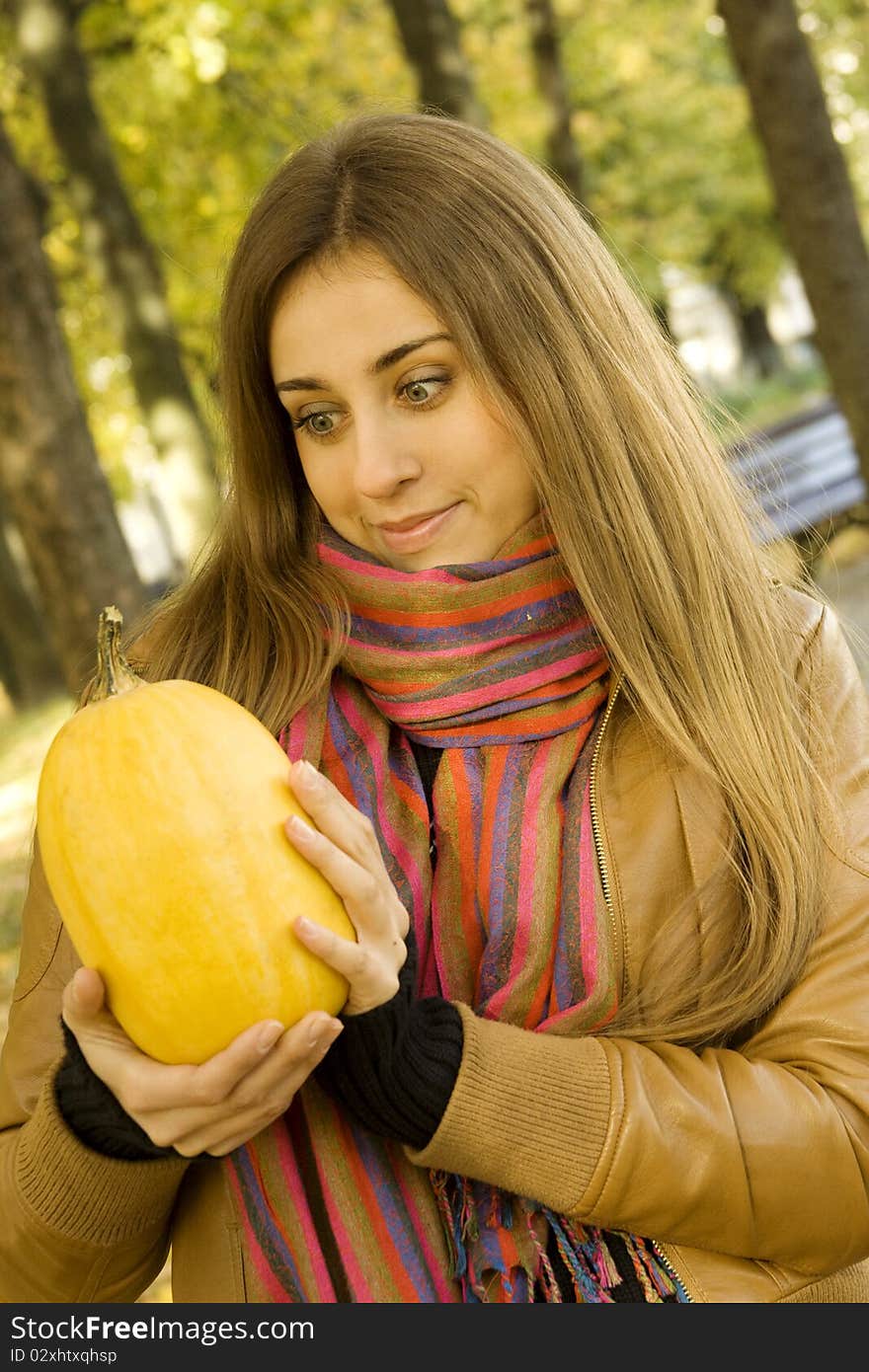 Smiling girl holding a pumpkin. Autumn on the street