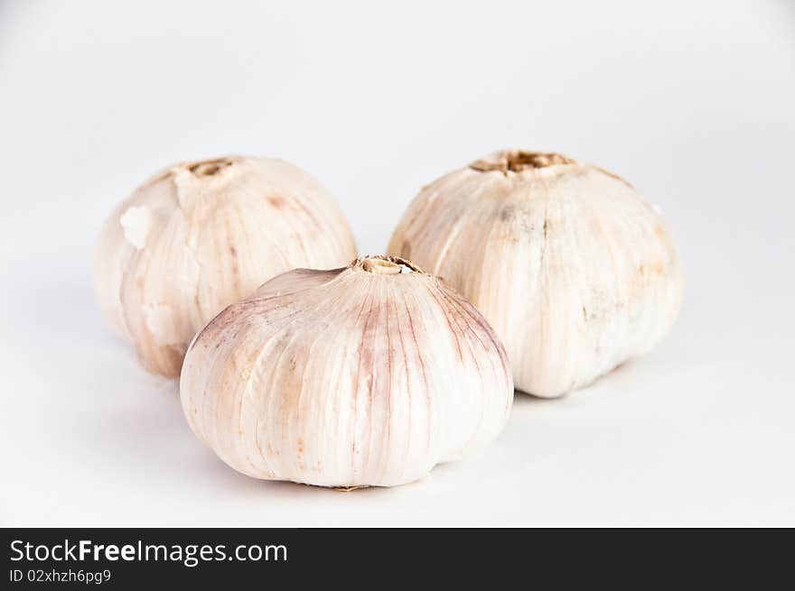 Three fresh, white garlic bulbs on white background