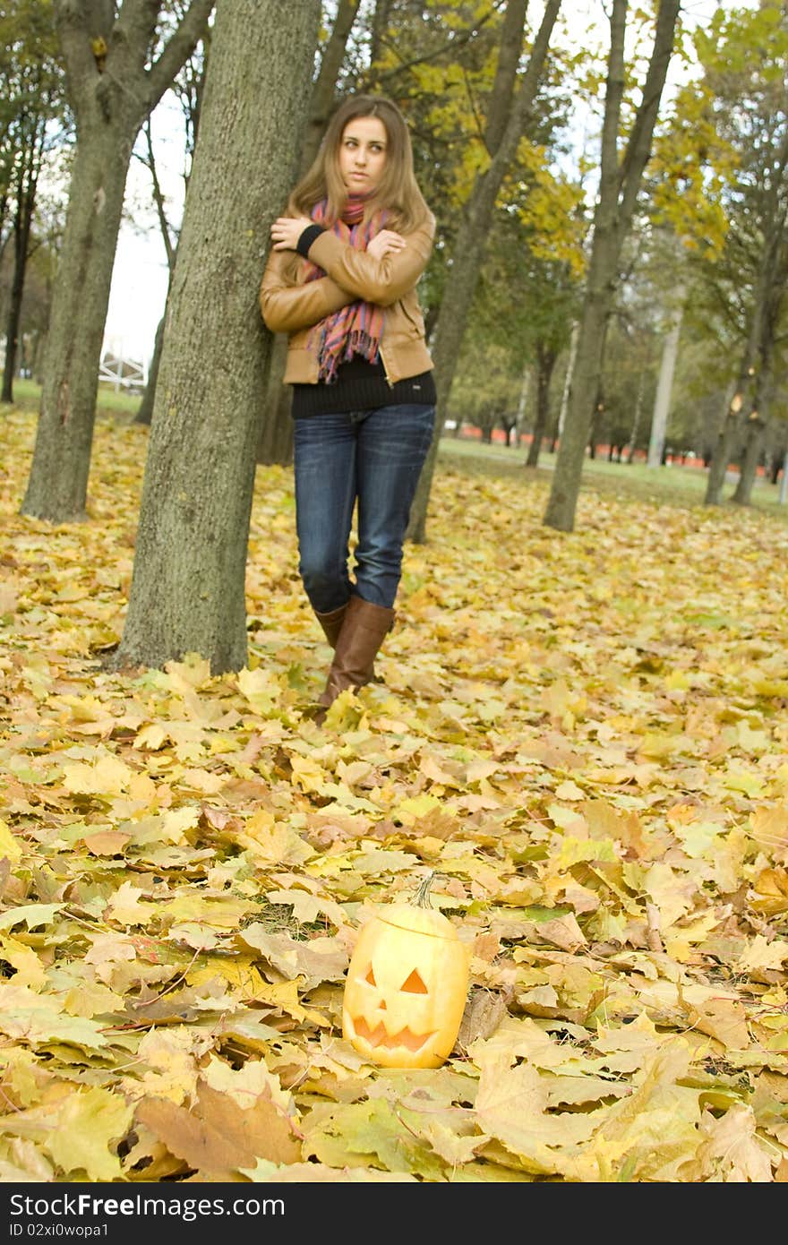 Young girl outdoors in autumn in the park with a pumpkin for Halloween