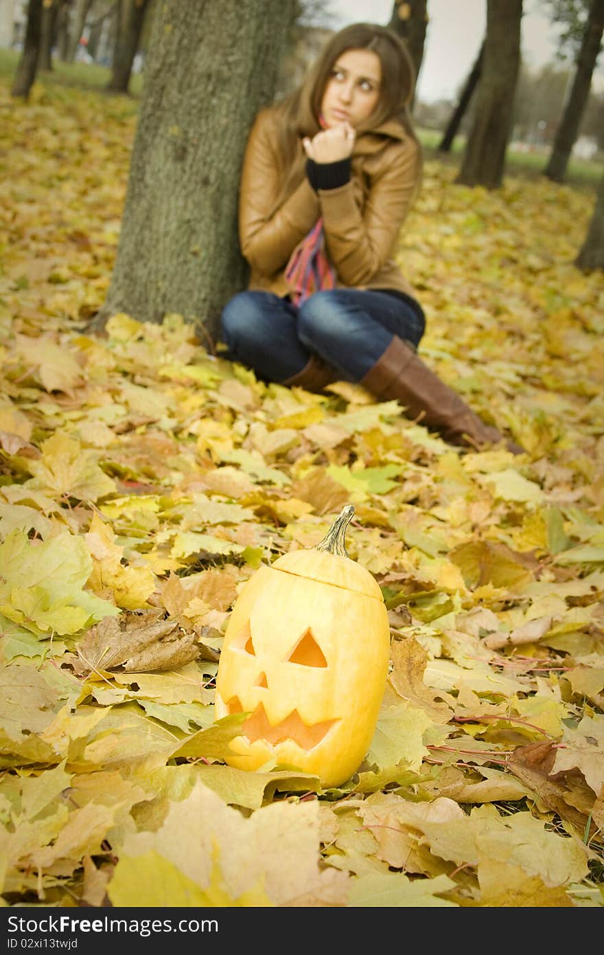 Young girl outdoors in autumn in the park with a pumpkin for Halloween