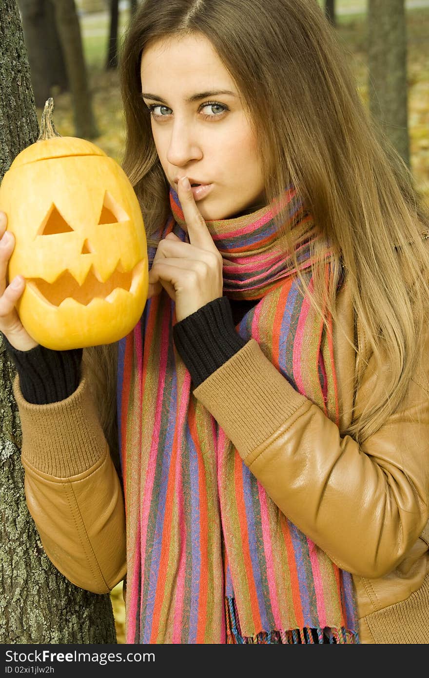 A young girl frightened with pumpkin for Halloween. Gesturing for Quiet or Shushing. Autumn on the street. A young girl frightened with pumpkin for Halloween. Gesturing for Quiet or Shushing. Autumn on the street