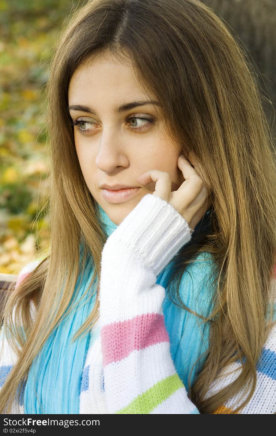 Portrait of a beautiful young woman sitting on a bench in the park around a lot of yellow, red green leaves. Portrait of a beautiful young woman sitting on a bench in the park around a lot of yellow, red green leaves