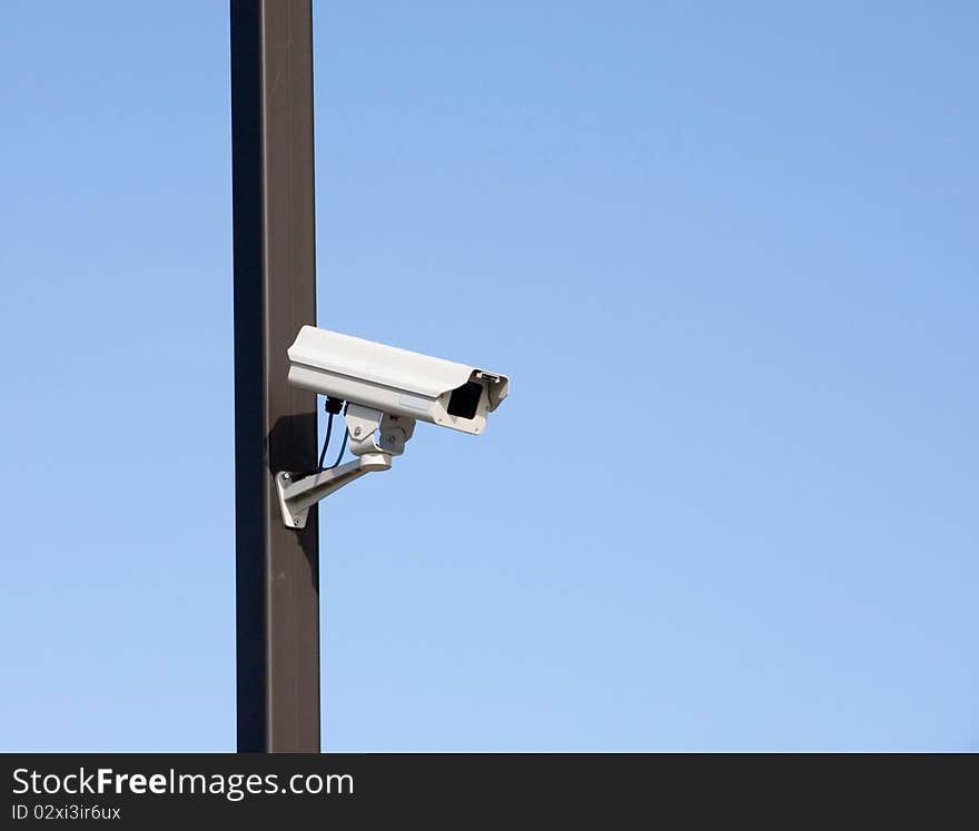 Surveillance camera on light pole in parking lot. Surveillance camera on light pole in parking lot