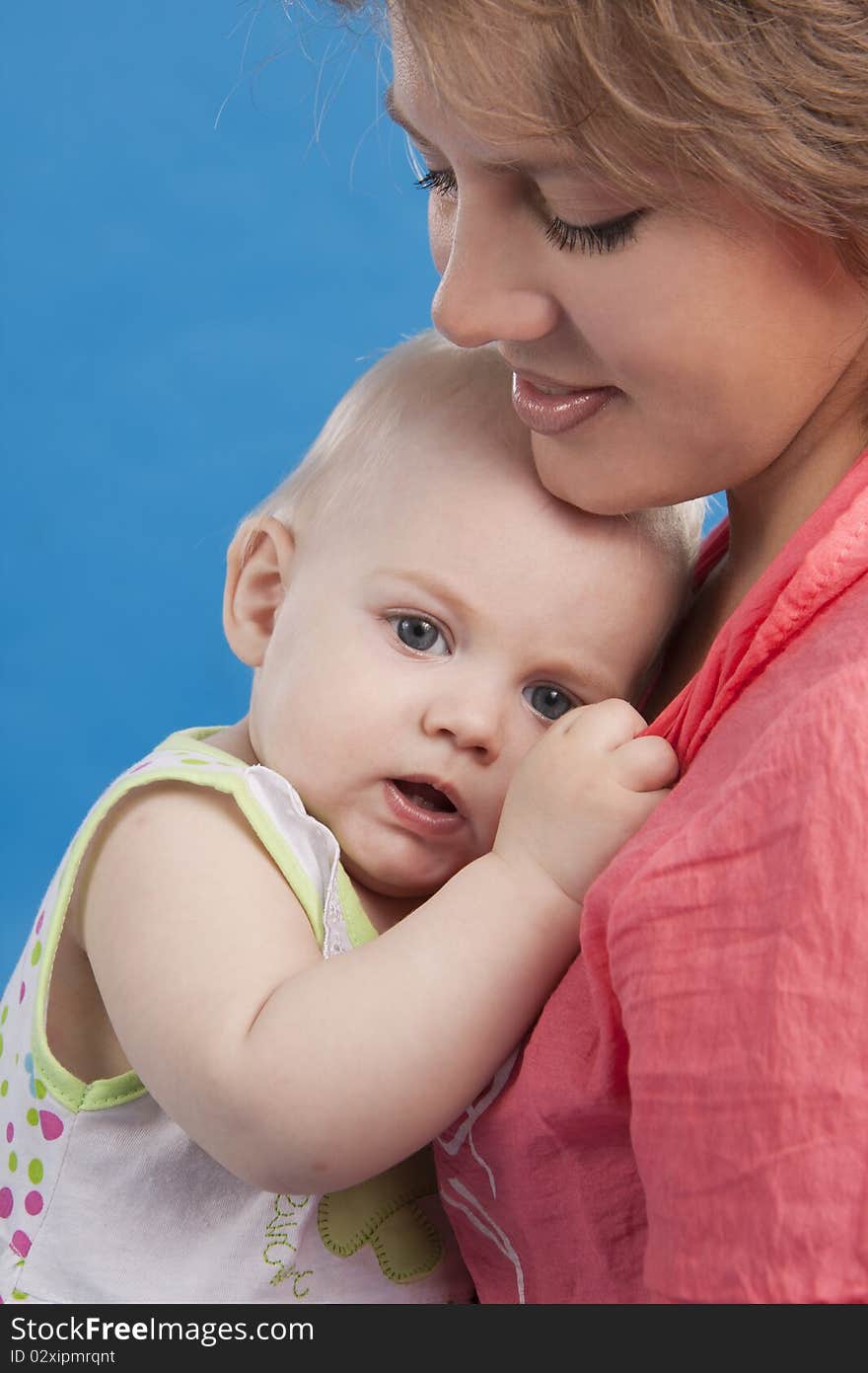 Young and beautiful mother with her sweet little daughter isolated on blue. Young and beautiful mother with her sweet little daughter isolated on blue.