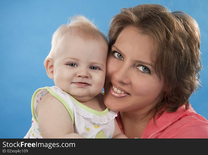 Young and beautiful mother with her sweet little daughter isolated on blue. Young and beautiful mother with her sweet little daughter isolated on blue.