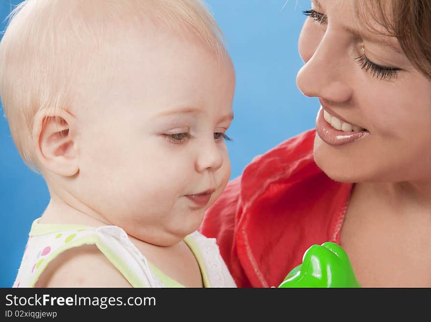 Young and beautiful mother with her sweet little daughter isolated on blue. Young and beautiful mother with her sweet little daughter isolated on blue.