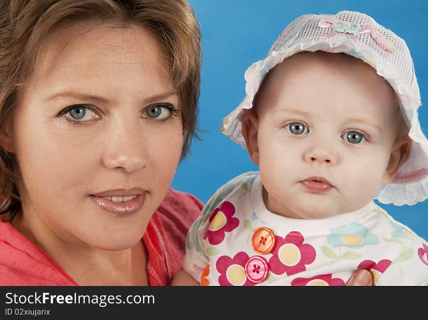 Young and beautiful mother with her sweet little daughter isolated on blue. Young and beautiful mother with her sweet little daughter isolated on blue.