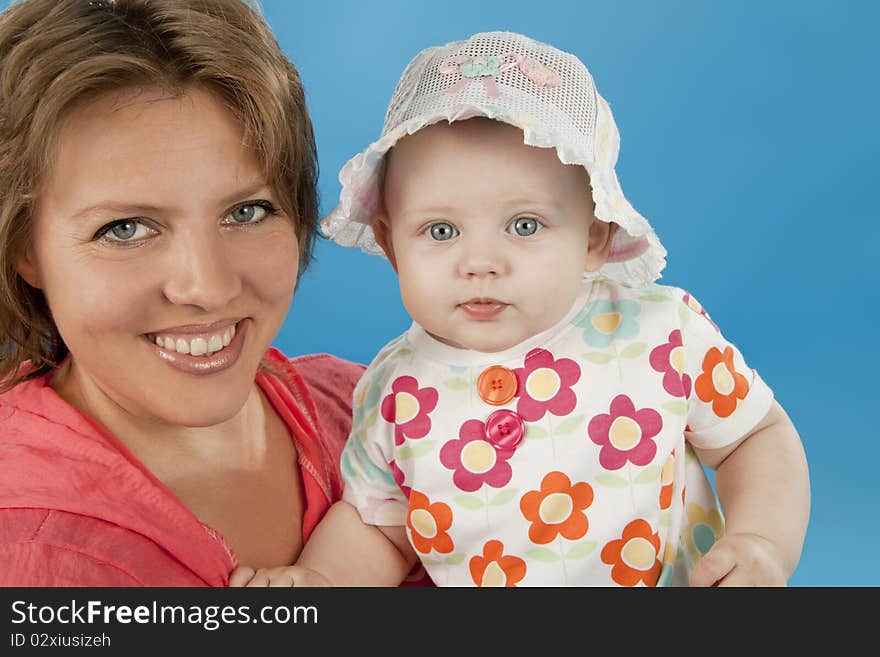 Young and beautiful mother with her sweet little daughter isolated on blue. Young and beautiful mother with her sweet little daughter isolated on blue.