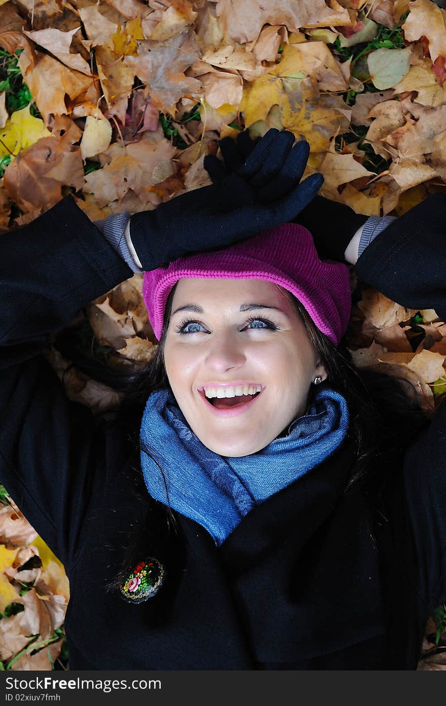 Pretty autumn girl relaxing outdoors in the forest on the fallen leafs