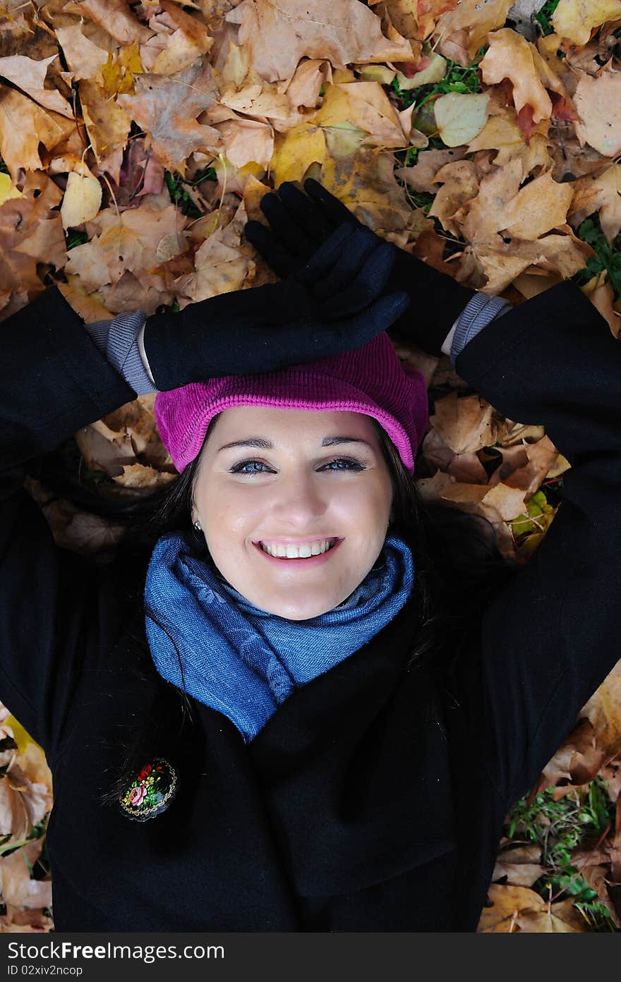 Pretty autumn girl relaxing outdoors in the forest on the fallen leafs