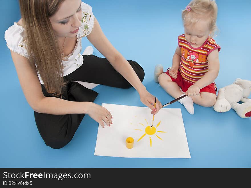 Mother and daughter draw paints the sun. Isolated blue. Mother and daughter draw paints the sun. Isolated blue.