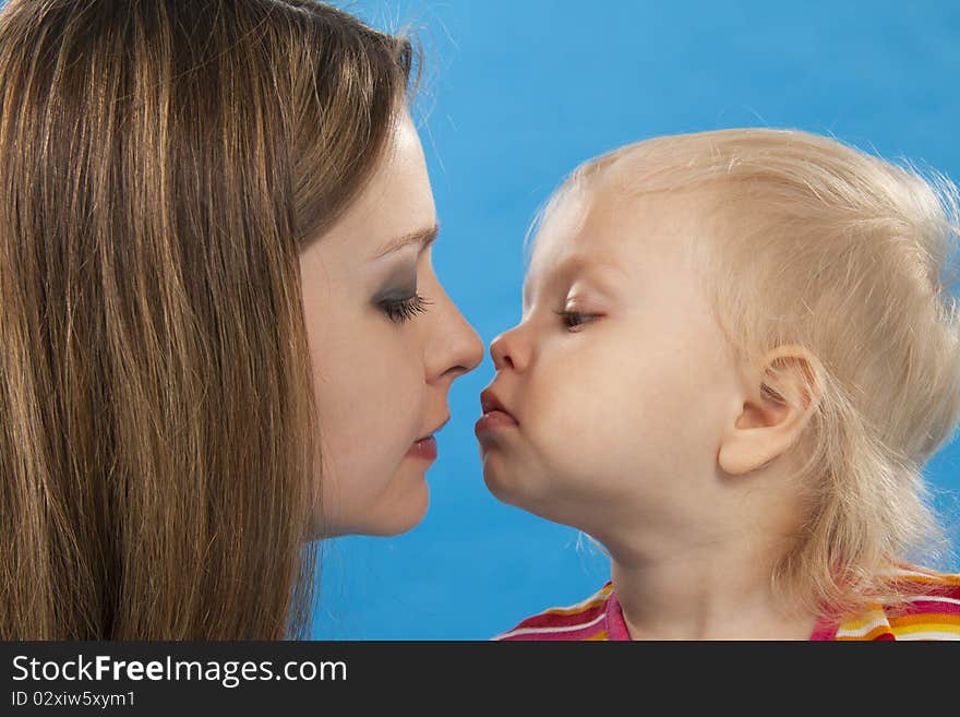 Young and beautiful mother with her sweet little daughter isolated on blue. Young and beautiful mother with her sweet little daughter isolated on blue.