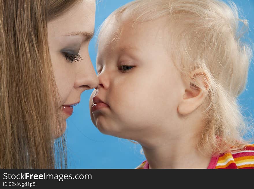 Young and beautiful mother with her sweet little daughter isolated on blue. Young and beautiful mother with her sweet little daughter isolated on blue.